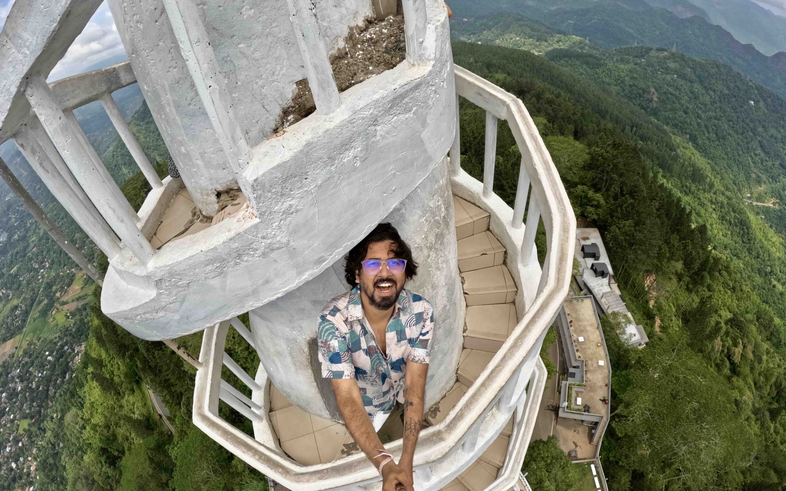A person standing on a white spiral tower with a steep valley below.
