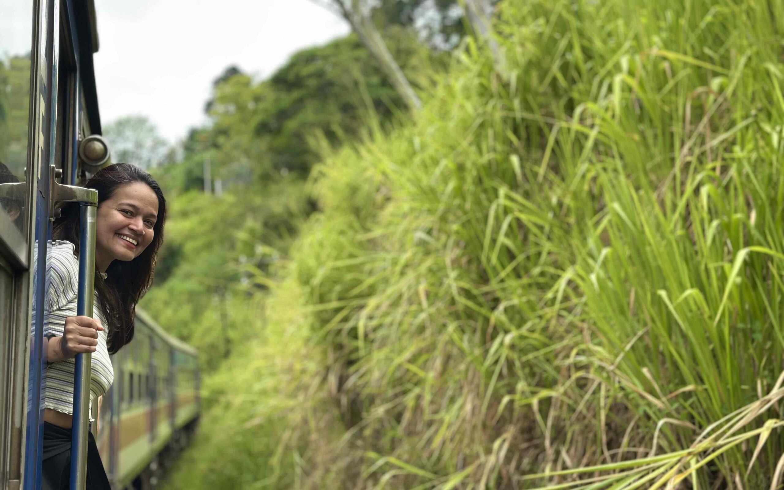 A person hanging out of the Ella Odyssey train in Sri Lanka