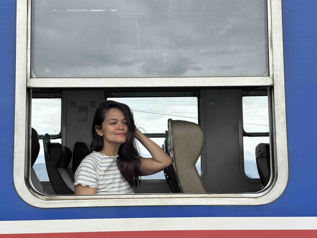 A person seated on the window of the blue Kandy to Ella train in Sri Lanka