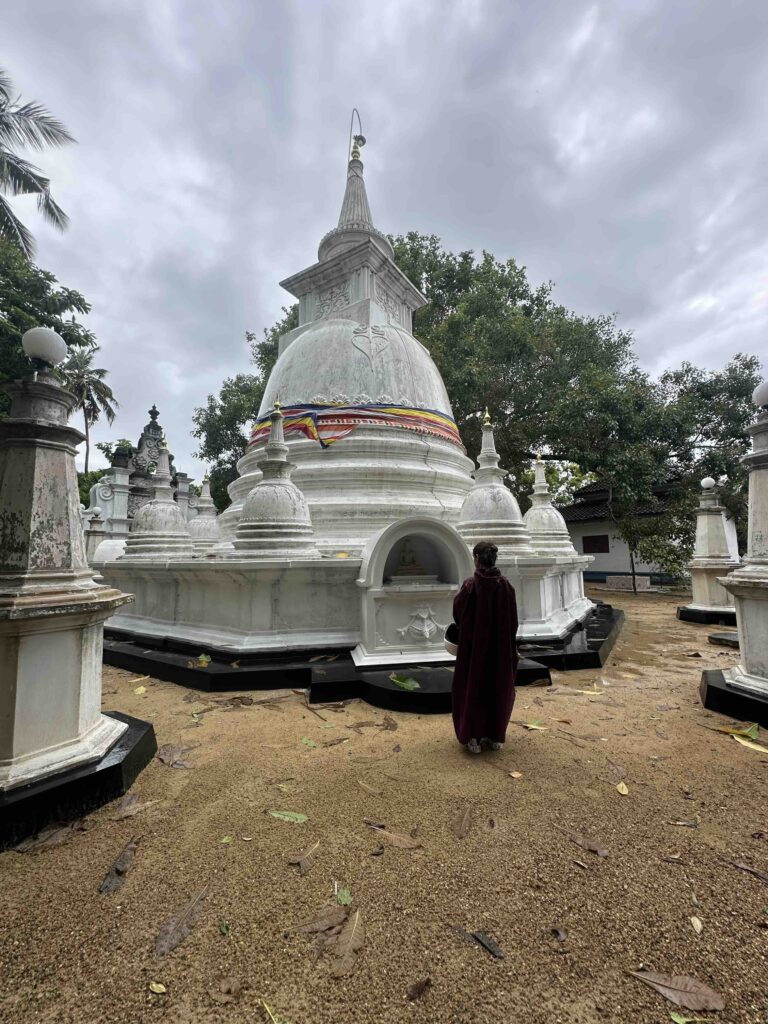 A person standing in front of a white stupa called Kathaluwa old temple in South Sri Lanka